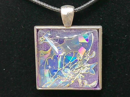 A square pendant necklace featuring a silver-toned frame and a black cord, with an iridescent purple and blue background and gold-toned fantasy line art, shown against a black background.