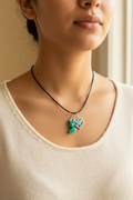A silver-toned double-pendant necklace displayed on a black velvet jewelry bust. The necklace features a heart-shaped pendant with iridescent multicolor crystals and a green stone cluster pendant.