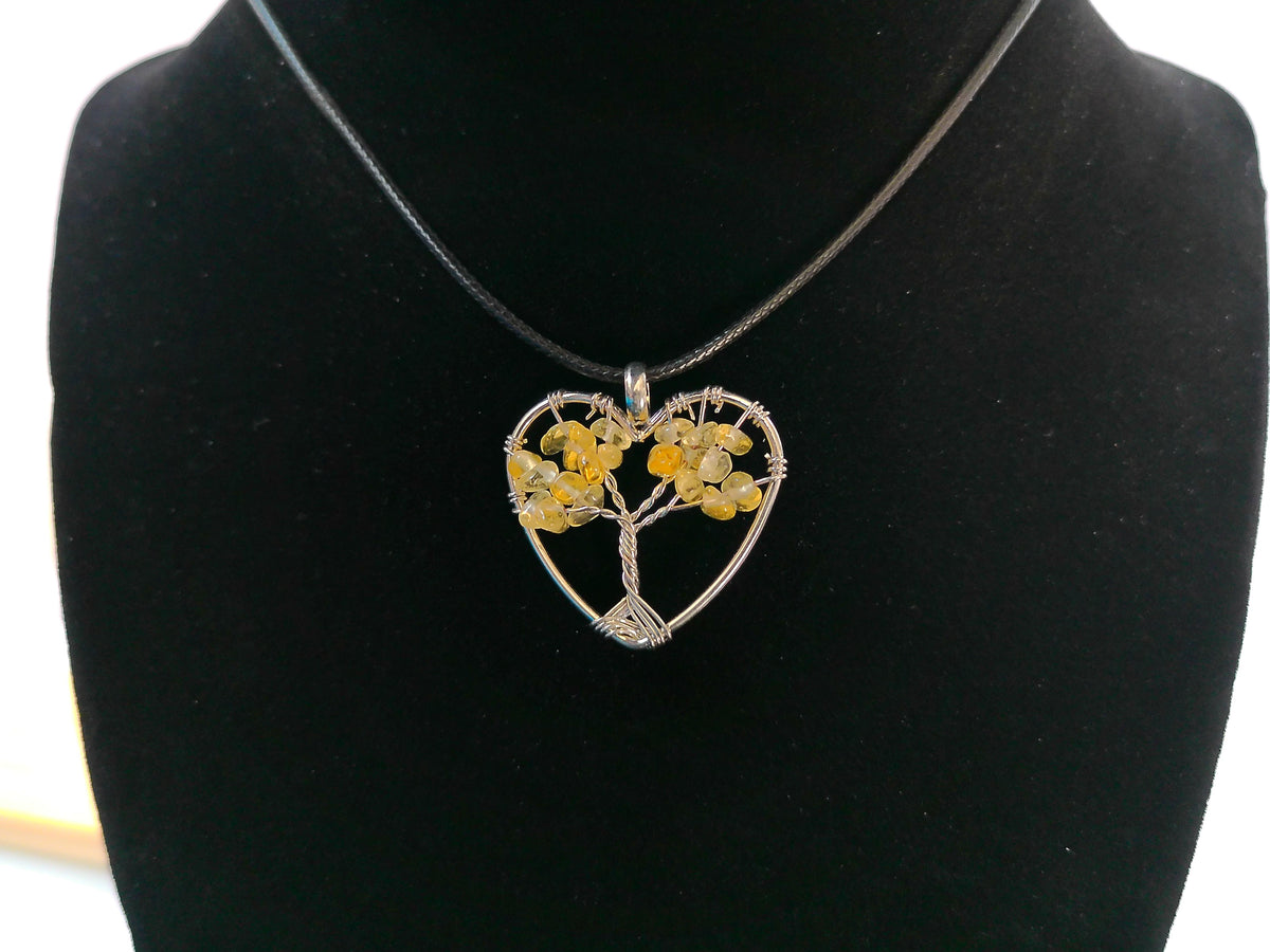 A heart-shaped tree of life pendant necklace with yellow flower details, displayed on a black velvet jewelry bust.