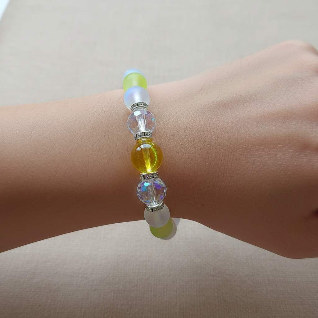 A beaded stretch bracelet displayed on a wooden circular scale. The bracelet features translucent frosted white beads, vibrant lime green beads, iridescent blue beads, and faceted clear beads with silver spacer rings.