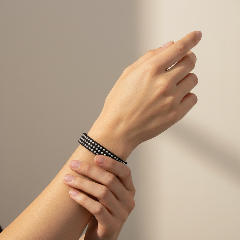 A black faux-leather bracelet embellished with rows of clear rhinestones, displayed on a light wood block engraved with '6.5in'.